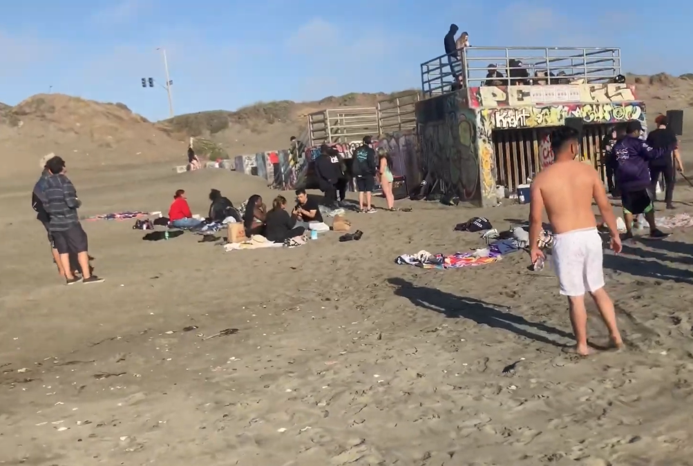 People in front of a grafittied cement beach structure